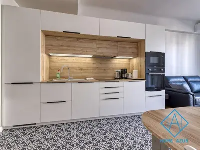 a kitchen with white cabinets and a black refrigerator at Golden Square in Nice