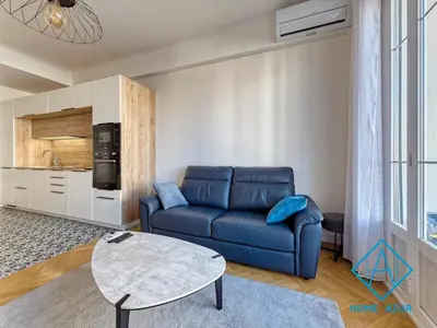 a living room with a blue couch and a table at Golden Square in Nice