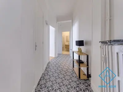 a hallway with a white wall and a floor with a table at Golden Square in Nice