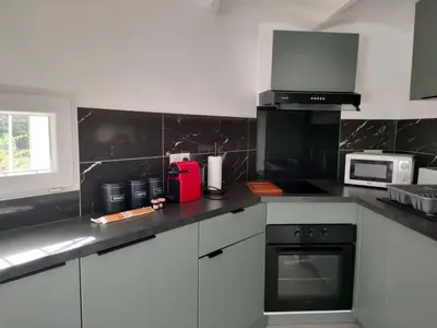 a kitchen with white cabinets and a black counter top at Appartement 2 pieces à Beaulieu-sur-Mer in Beaulieu-sur-Mer