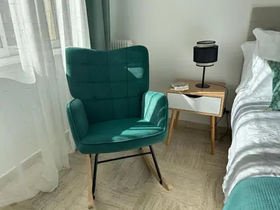 a green chair sitting in a bedroom next to a bed at Superbe appartement Port de Nice Lumineux,Clim , Parking in Nice