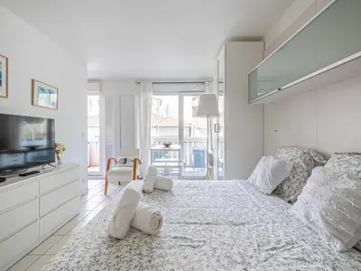 a white bedroom with a large bed and a tv at Studio with balcony & pool -Heart of Nice in Nice