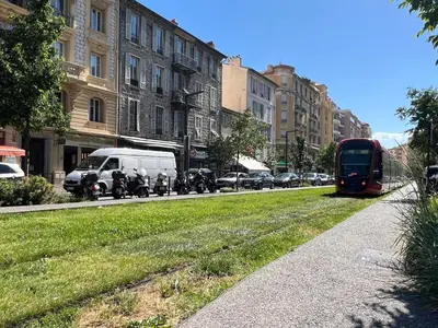a red bus driving down a city street with buildings at Studio toit terrasse vue mer Sea View in Nice