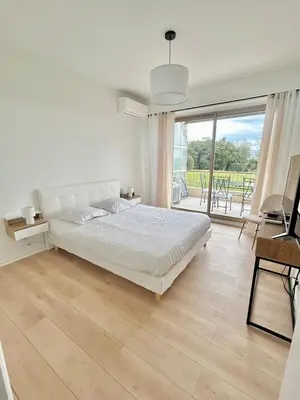 a white bedroom with a bed and a large window at Le Grand Soleil in Nice