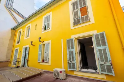a yellow building with white windows and a door at Le Jasmin - Au Coeur de Nice in Nice