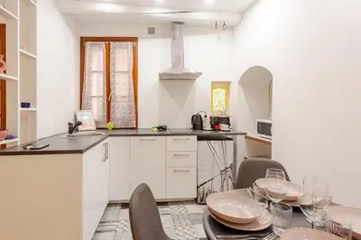 a kitchen with a table and some chairs and a counter at Cocon charmant et paisible au cœur du Vieux Nice in Nice