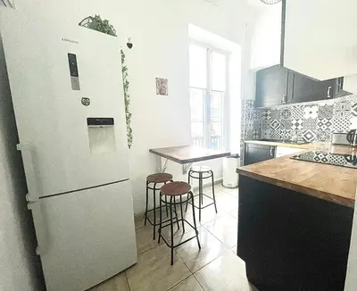 a kitchen with a refrigerator and a table with stools at Cosy Family trip in Nice