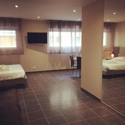 a hotel room with two beds and a dining room at Villa Serafina Apartements in Nice