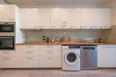 a kitchen with white cabinets and a washing machine at Guest House Chez Bastien in Nice
