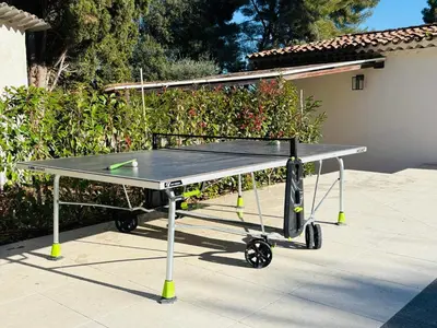 a ping pong table with a tennis racket on it at L'Esprit Sud, 4 Suites & Piscine Chauffée in Vence