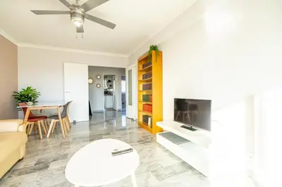a living room with a couch and a tv and a table at Sea & City View in Nice