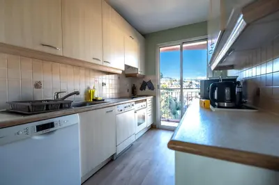 a kitchen with white cabinets and a large window at Sea & City View in Nice