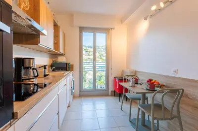 a kitchen with a table with chairs and a counter top at LE SAINT ESTEVE AP4435 By Riviera Holiday Homes in Villefranche-sur-Mer