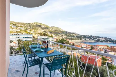 a table on a balcony with a view of the ocean at LE SAINT ESTEVE AP4435 By Riviera Holiday Homes in Villefranche-sur-Mer