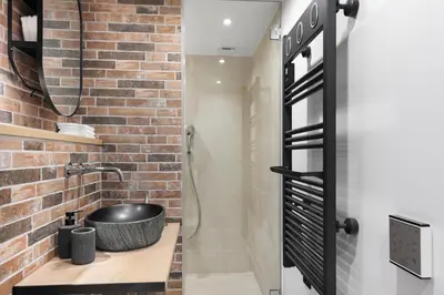 a bathroom with a sink and a brick wall at Loft Industriel avec Terrasse et Filet Suspendu à Nice Cimiez in Nice