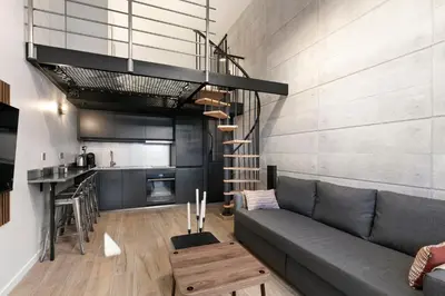 a living room with a gray couch and a kitchen at Loft Industriel avec Terrasse et Filet Suspendu à Nice Cimiez in Nice