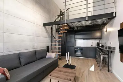 a living room with a gray couch and a kitchen at Loft Industriel avec Terrasse et Filet Suspendu à Nice Cimiez in Nice