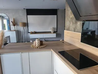 a kitchen with white cabinets and a tv on the wall at Maison entre mer et montagnes in La Gaude