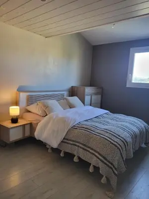 a bedroom with a bed and a table with a lamp at Maison entre mer et montagnes in La Gaude