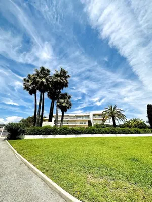 a park with palm trees in front of a building at Superbe studio front de mer in Saint-Laurent-du-Var