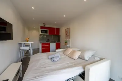 a large bed in a small room with red cabinets at Superbe studio front de mer in Saint-Laurent-du-Var