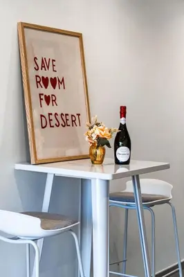 a table with a bottle of wine and two stools at Superbe studio front de mer in Saint-Laurent-du-Var