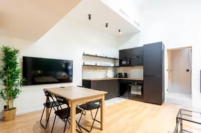 a kitchen with a wooden table and black appliances at Loft Spacieux pour 10 personnes avec Terrasse in Nice