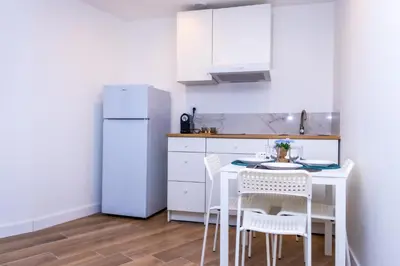 a kitchen with a table and chairs and a white refrigerator at NIce proche mer in Nice