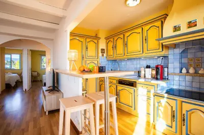 a kitchen with yellow cabinets and wooden floors at LE JARDIN BLEU AP4388 By Riviera Holiday Homes in Nice