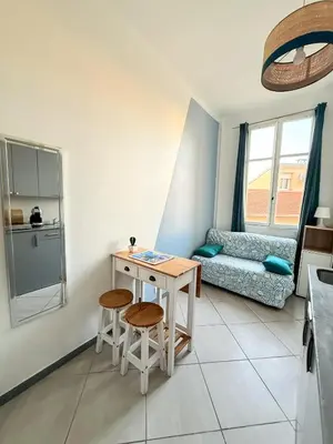 a living room with a table and two stools at PORT - Charmant Studio in Nice