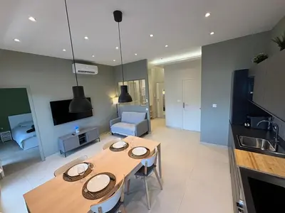 a kitchen and living room with a table and a couch at NICE La Palmeraie Pool BEACH AC in Nice