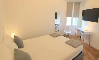 a bedroom with a bed and a desk and a computer at Happyfew Le Miramar in Nice