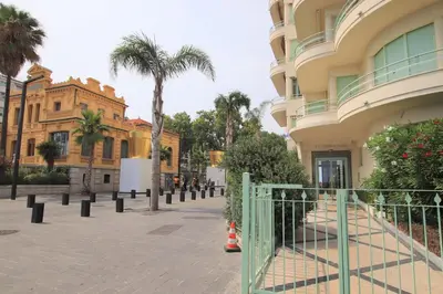 a street with palm trees and a building at Happyfew Le Miramar in Nice