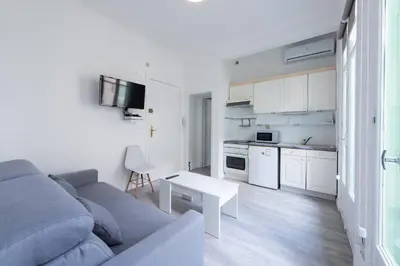 a living room with a gray couch and a white kitchen at Happyfew Le Miramar in Nice