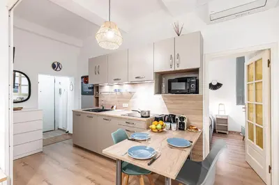 a kitchen with a wooden table with chairs and a dining room at FEEL HOME - Poissonnerie in Nice