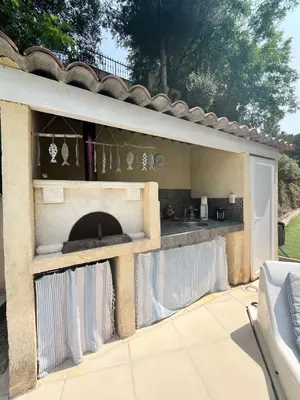 a outdoor kitchen with a stone fireplace in a yard at Sur les hauteurs de Nice, belle villa idéale en famille ou entre amis in Colomars