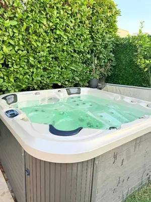 a jacuzzi tub in front of a bush at Maison avec jacuzzi privatif dans résidence in La Gaude