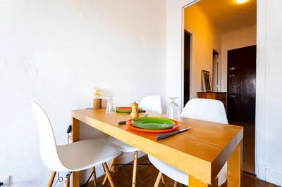 a dining room table with a green plate and white chairs at Il Sole e Mare in Nice