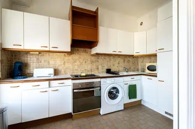a kitchen with white cabinets and a washing machine at Il Sole e Mare in Nice