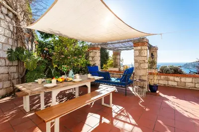 a patio with a wooden bench and a table at CASA ROSALIE VI4442 By Riviera Holiday Homes in Villefranche-sur-Mer