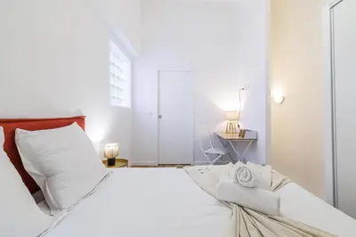 a white bedroom with a large bed with white pillows at 1 Bdr Duplex Downtown - AC in Nice