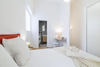 a white bedroom with a bed and a table at 1 Bdr Duplex Downtown - AC in Nice