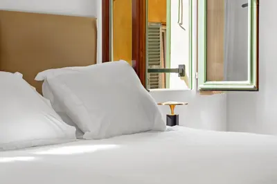 a white bed with white pillows and a window at Saint-Augustin - Nice Old Town in Nice