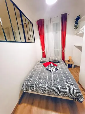 a bed in a room with red curtains at Studio T1 Centre - Idéal couple & amis - Confort - WIFI - Calme - Climatisation - Coin Terrasse in Nice