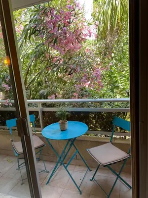 a blue table and chairs on a balcony with flowers at Les Magnolias 06 in Nice