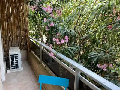 a balcony with a blue chair and pink flowers at Les Magnolias 06 in Nice
