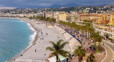 a view of a beach with palm trees and the ocean at Votre COCON Niçois Appart Vue Mer in Nice