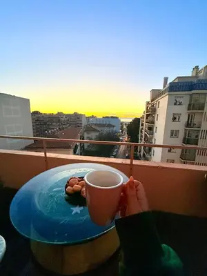 a person holding a cup of coffee on a balcony at Votre COCON Niçois Appart Vue Mer in Nice