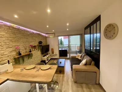 a living room with a couch and a clock on a wall at F1 Saint Laurent du Var Proximity to beach-Clim Wifi in Saint-Laurent-du-Var