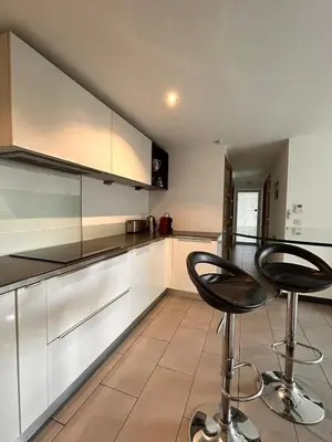 a kitchen with two bar stools in front of a counter at Proche bord de mer, au calme, nature avec piscine in La Gaude